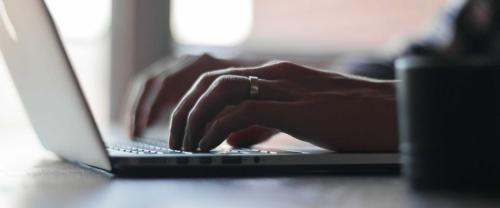 Hands typing at laptop