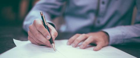 Man writing at desk with pen